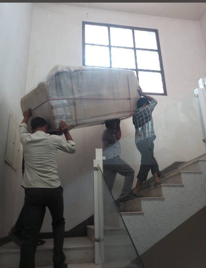 Movers carrying wrapped sofa up the stairs